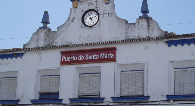 Fachada de la estación del Puerto de Santa María con un reloj en la parte superior y ventanas blancas
