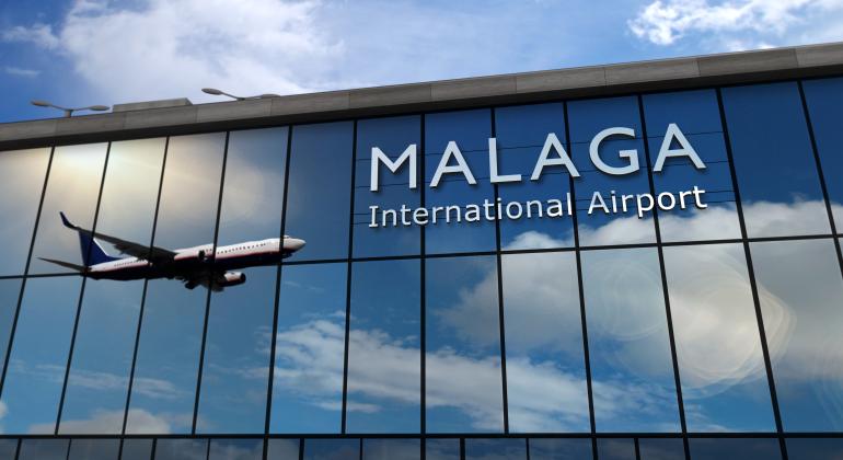 Frontal del Edificio del Aeropuerto de Málaga con unas cristaleras que contiene unas letras blancas que forman la palabra Málaga International Airpot y se refleja un avión