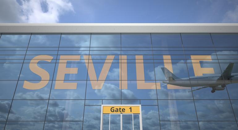 Frontal del Edificio del Aeropuerto de Sevilla con unas cristaleras que contiene unas letras amarillas que forman la palabra Sevilla