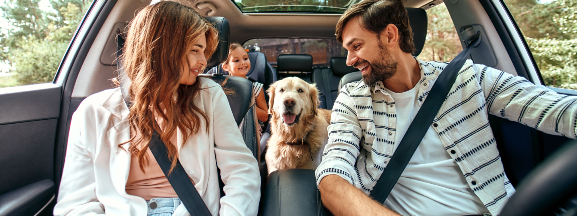 Familia dentro de un coche, mirando todos a su perro situado en el centro