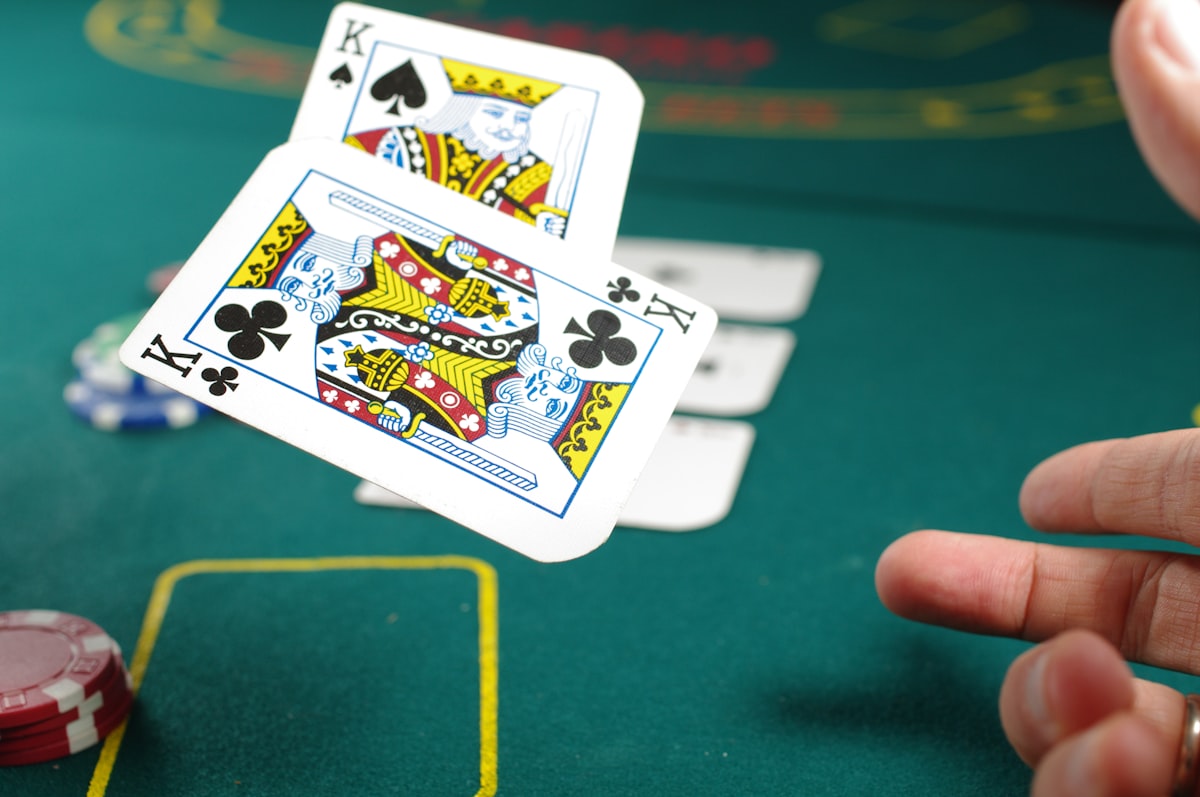 Mano con cartas y fichas en mesa de blackjack